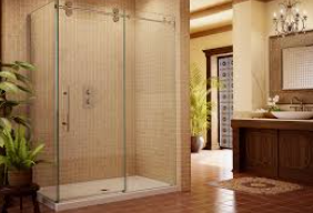 Glass shower stall in a bathroom, with a sink, wooden vanity, and tiled floor.