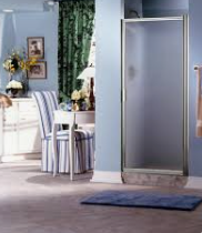 Shower with frosted glass door in a blue-walled bathroom, next to a chair and a window with green curtains.