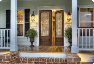 Front porch with open double doors, sidelights, lanterns, brick steps, and planters.