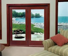 Double glass doors opening to a scenic lake view with a grill on the patio and a couch inside.