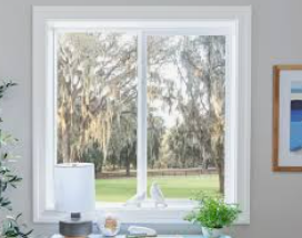 White-framed window with a view of trees with hanging moss. A desk with items sits below the window.