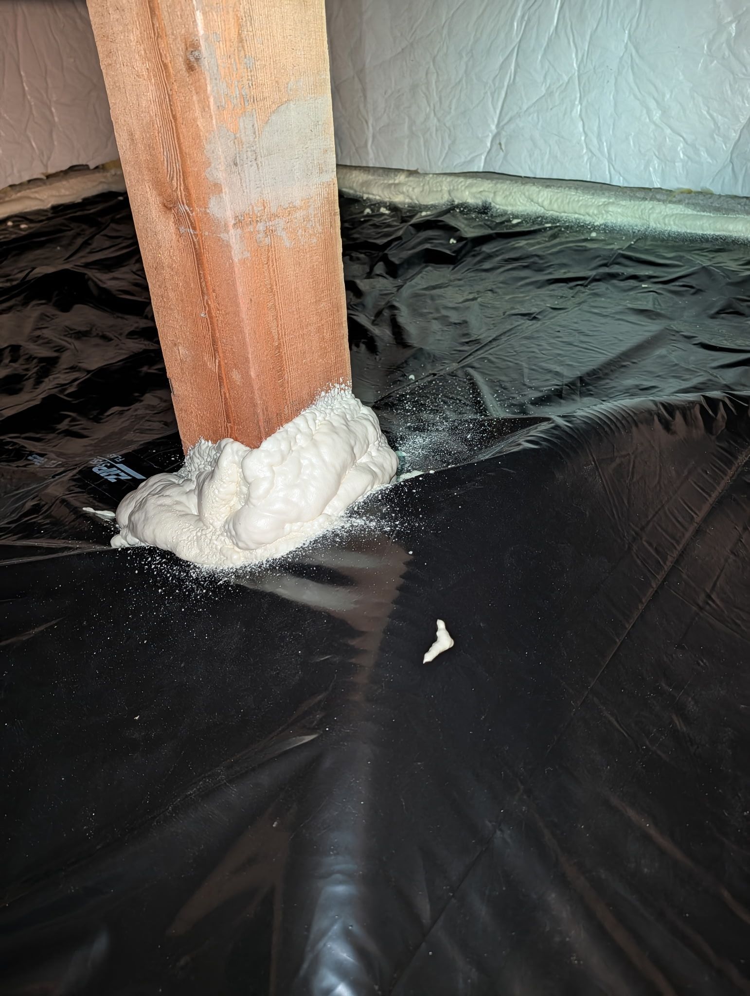 Foam sealing around a wooden post where it meets a black floor covering