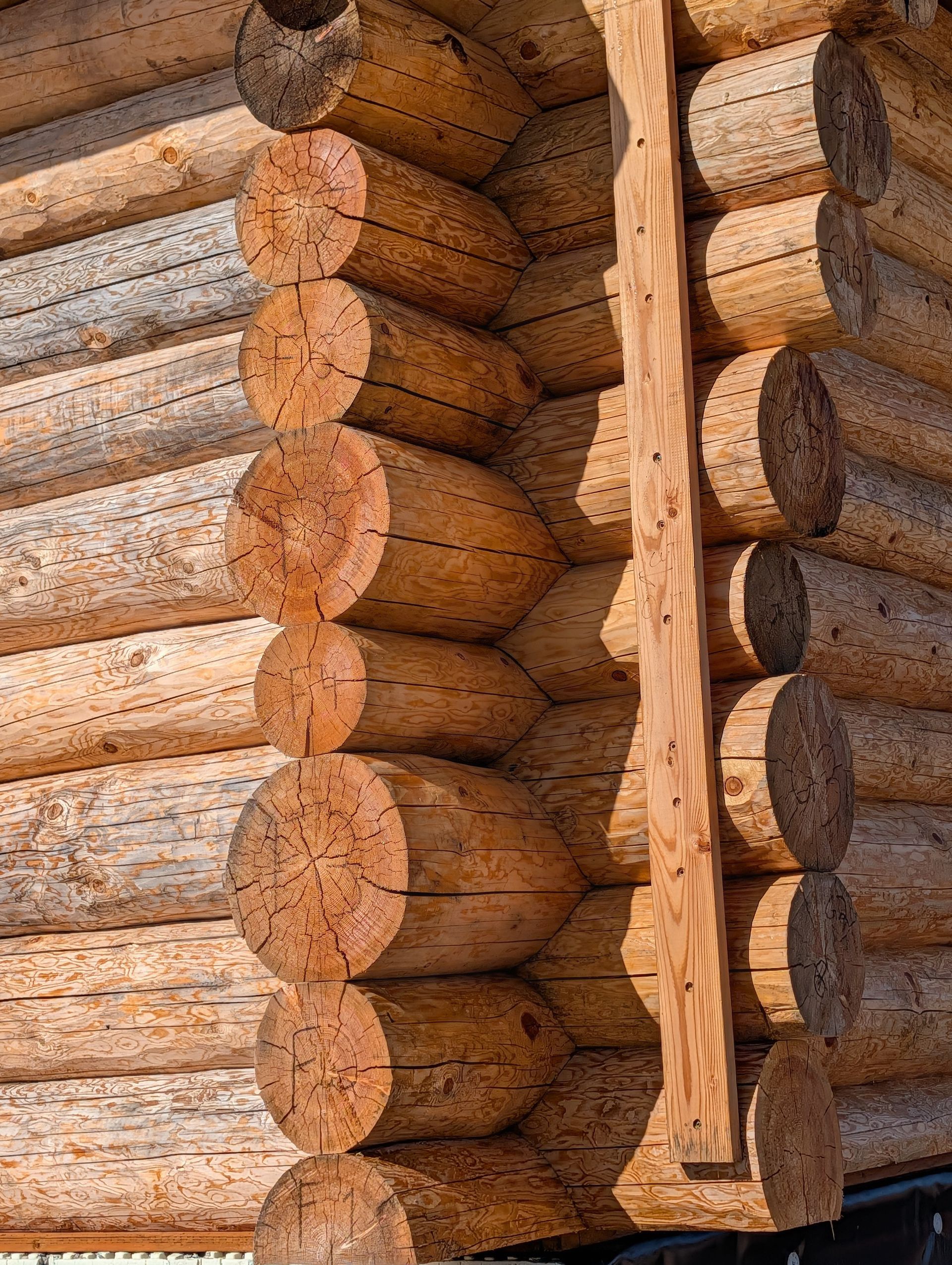 Stacked round log cabin walls with a vertical wooden corner brace