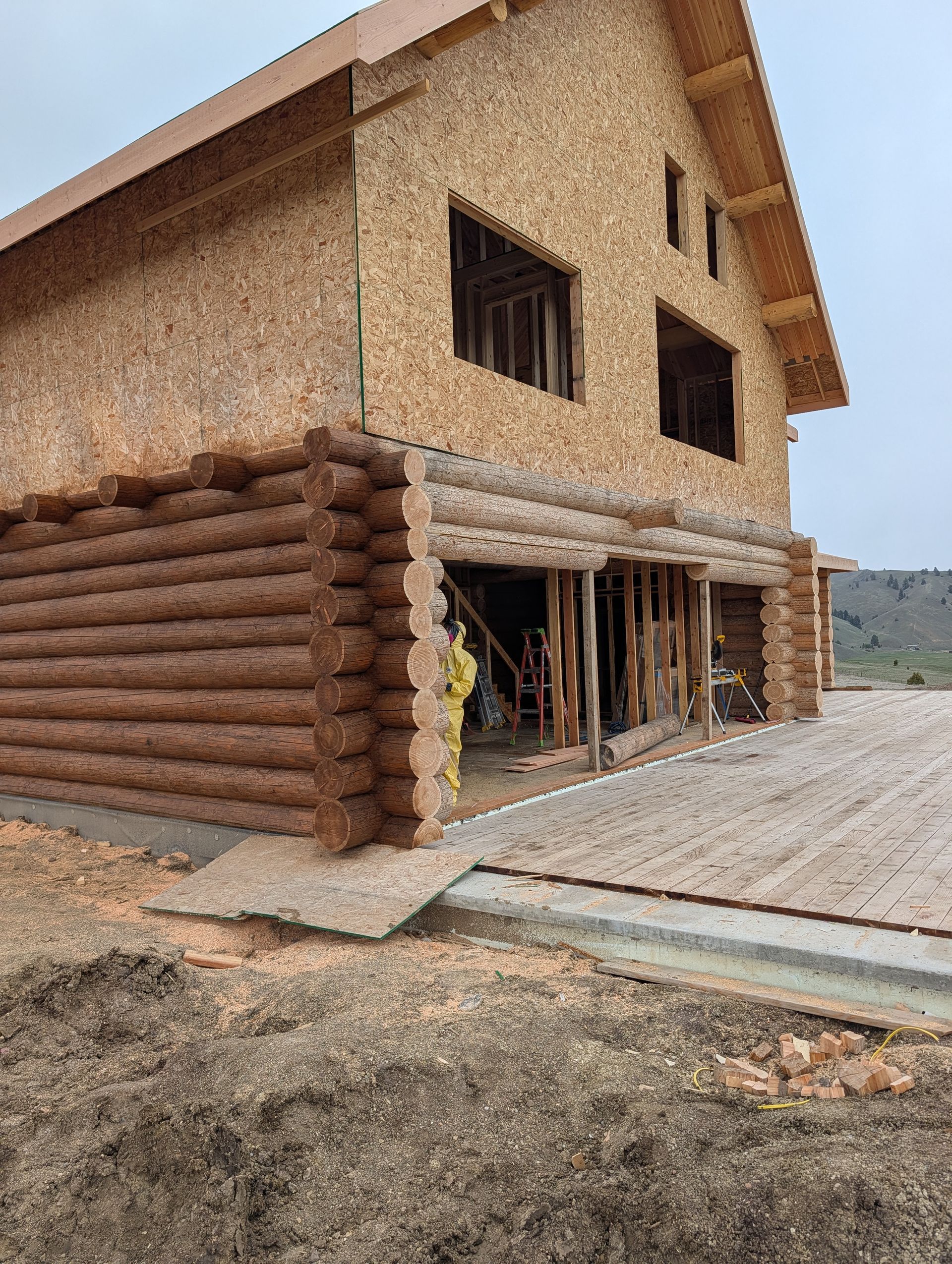 Partially built two-story brick and timber house with open ground floor and paved driveway
