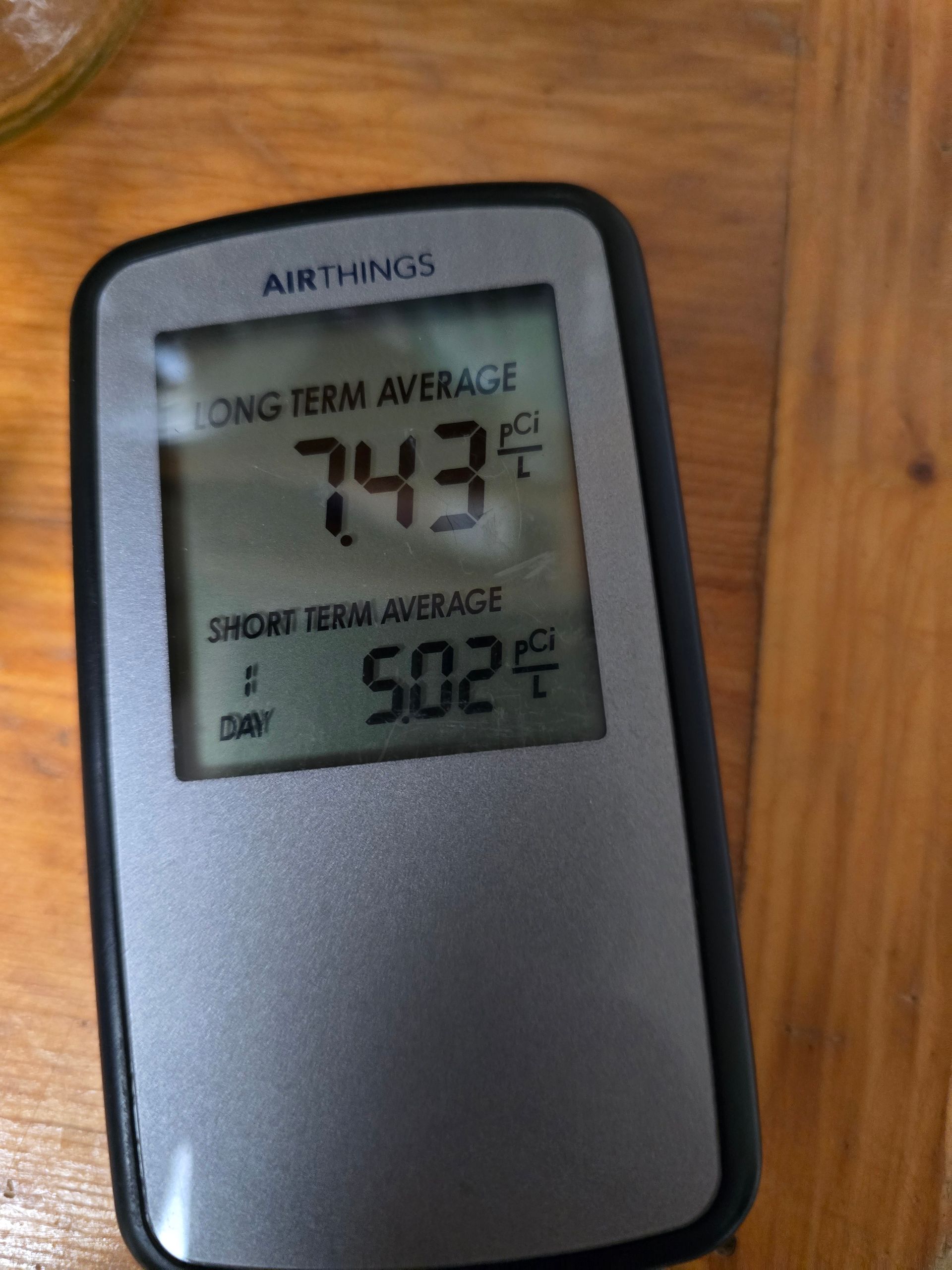 Black AirThings air quality monitor on wood table showing 74.3°F and 50.2% humidity