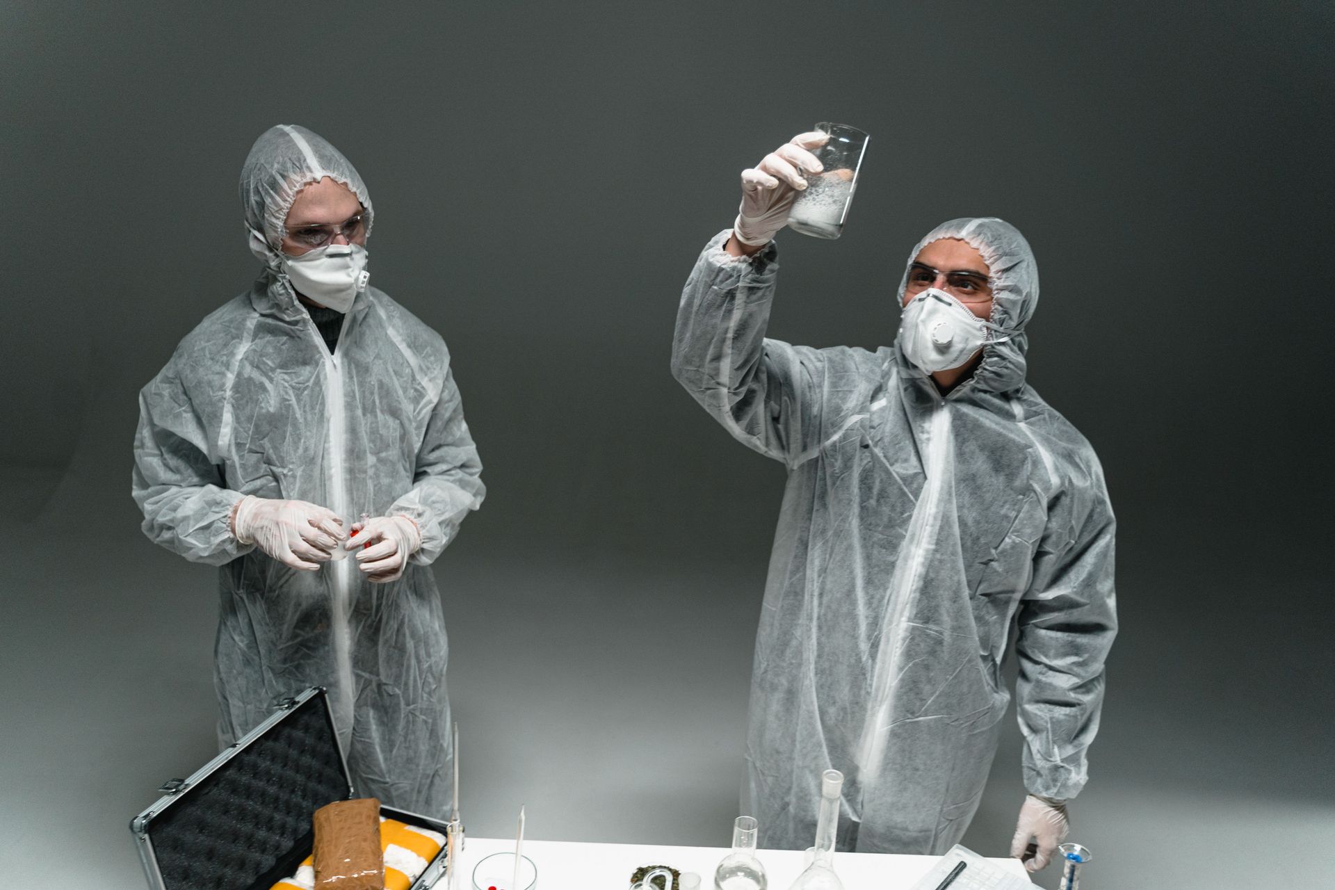 Two workers in protective gear inspecting a rooftop drain near a crouching woman by a wall.