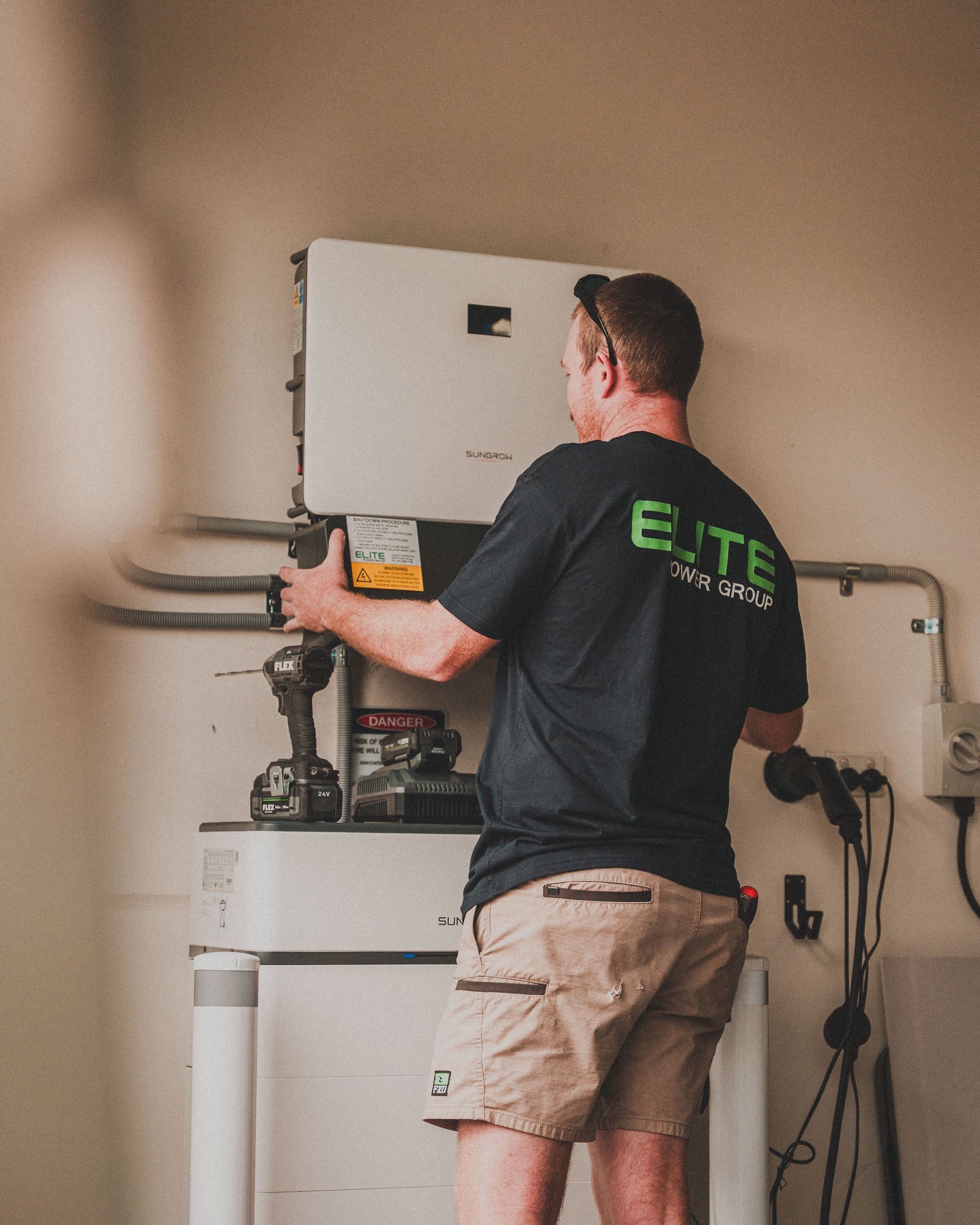 Technician servicing a wall-mounted unit in a beige utility room
