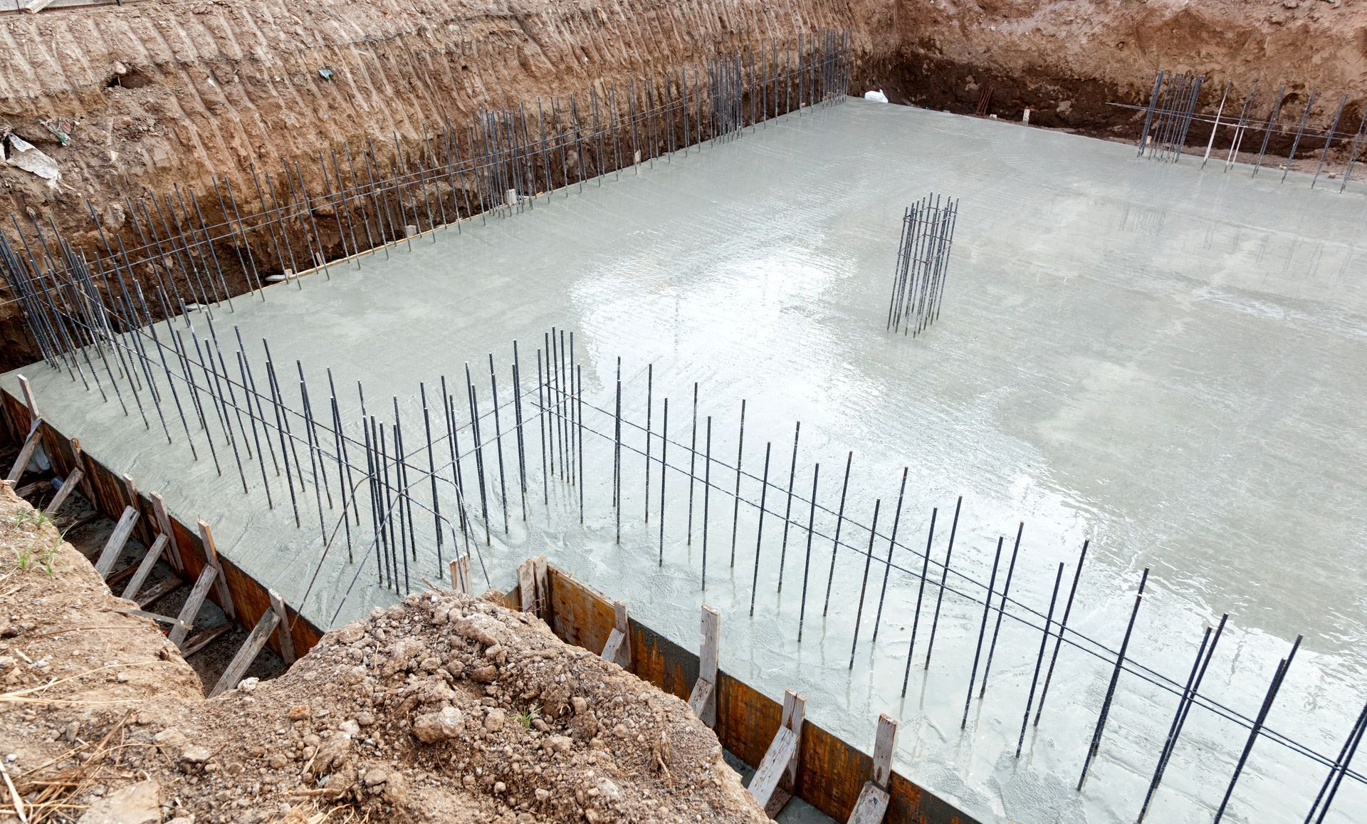 A large concrete slab is being poured into a hole in the ground.