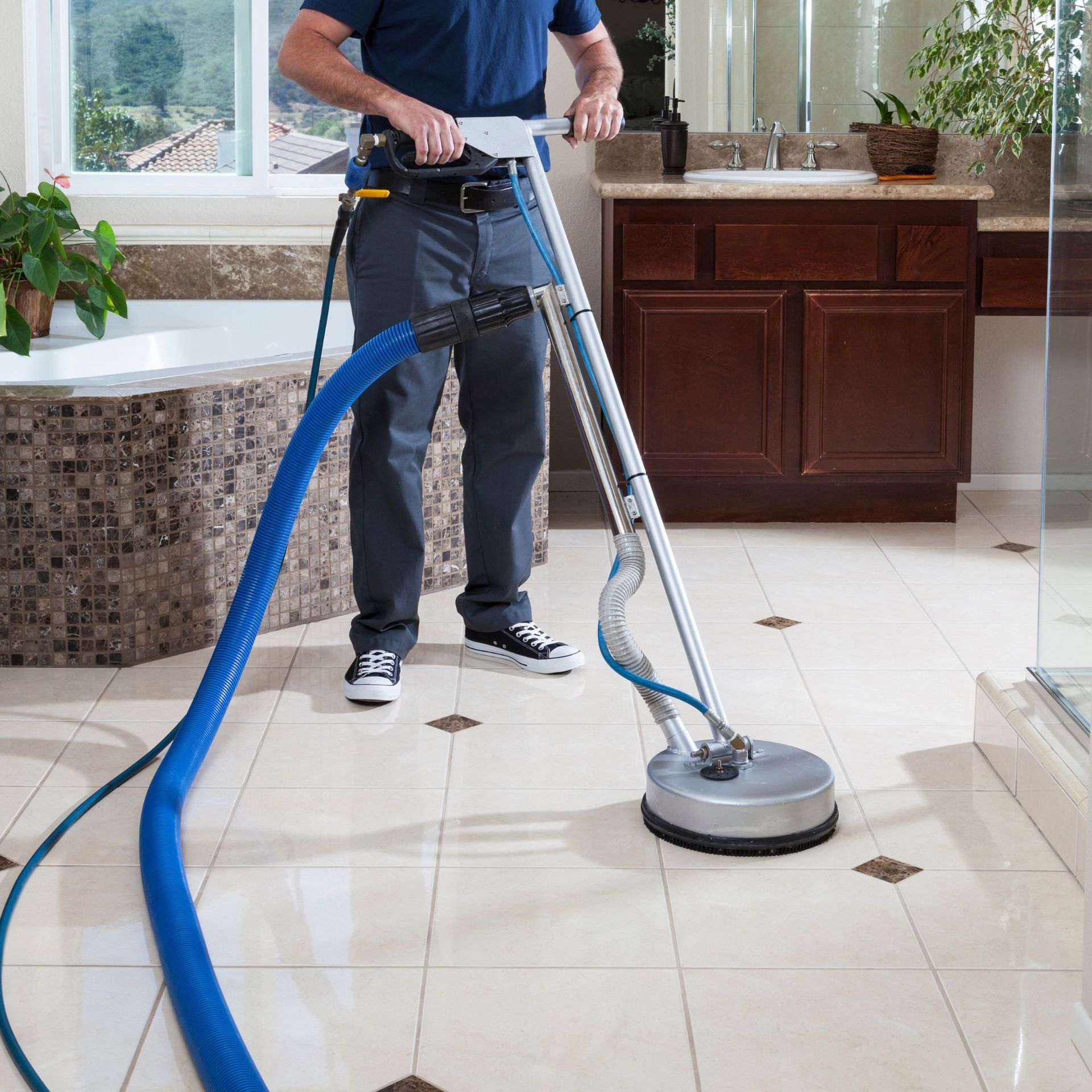 Arizona Carpet and Tile Steamers, Inc.- A person wearing orange gloves is cleaning a tile floor with a sponge.