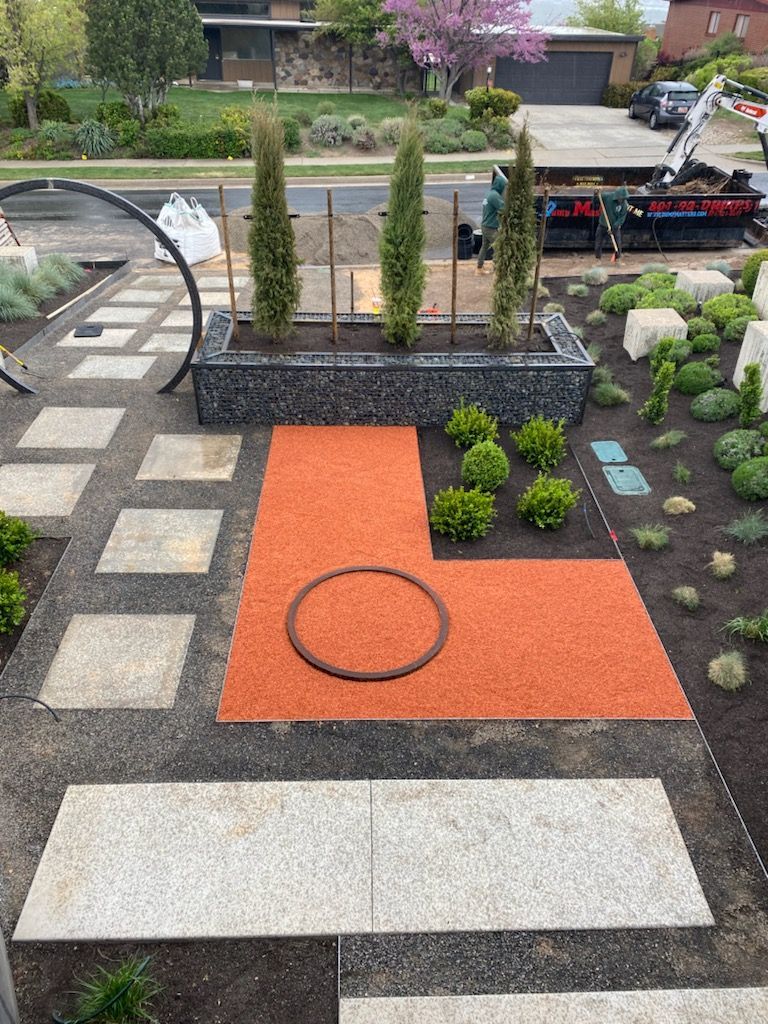 Modern landscape with orange and gray paving stones, gravel, and Cypress trees.