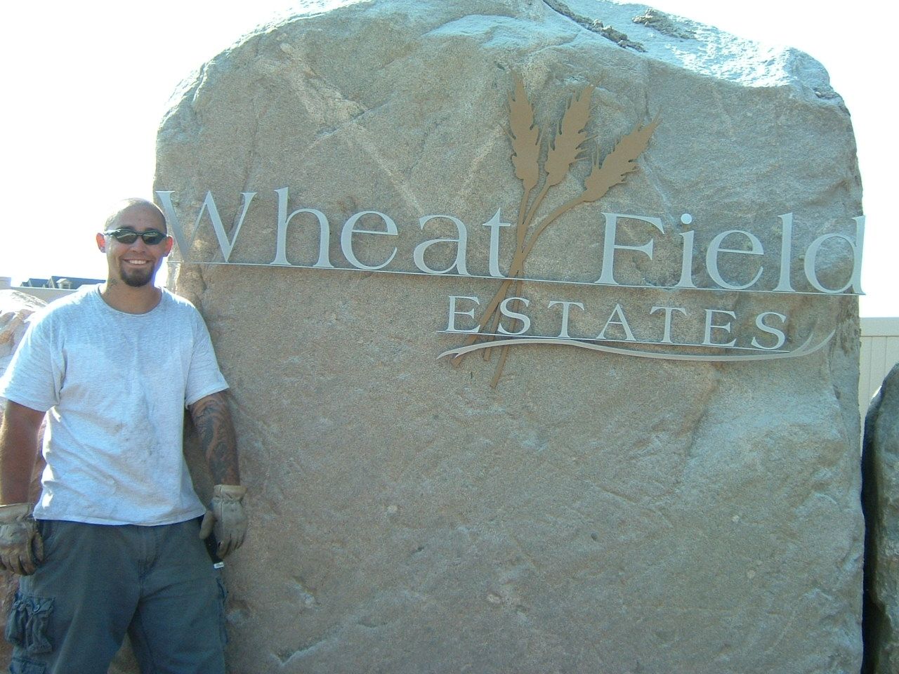 Man stands beside a large rock sign that reads 