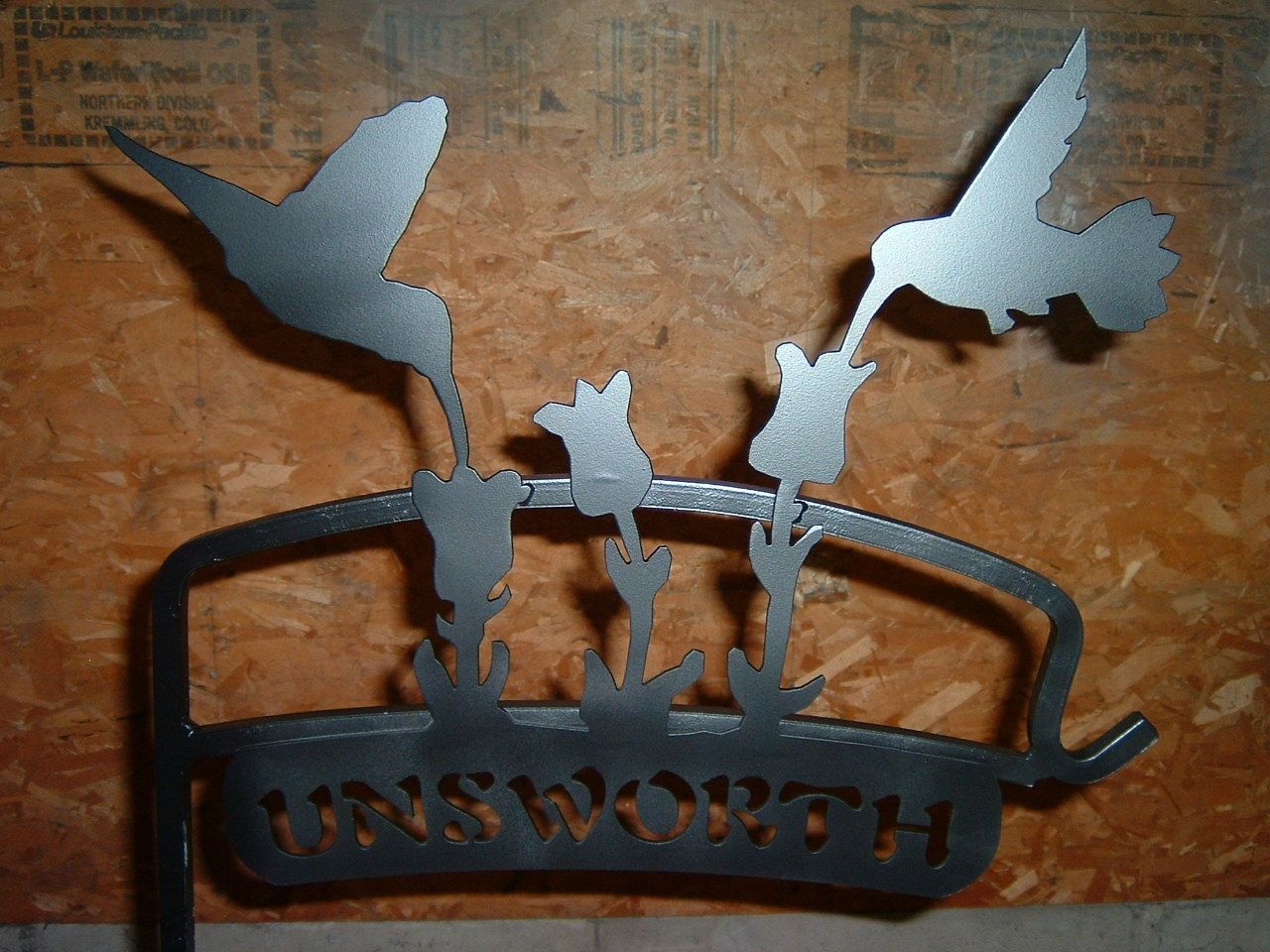 Metal hummingbird garden stake with two birds drinking from flowers and the name 