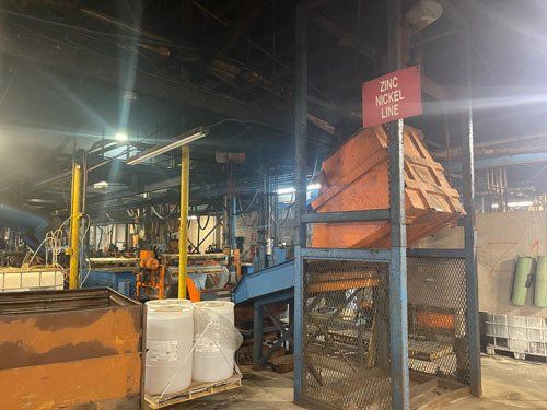 Industrial workspace with orange machinery, white containers, and a red warning sign under bright lights