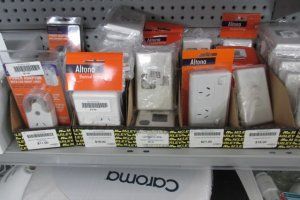 Electrical outlets and wall plates in orange retail packaging displayed on a store shelf.
