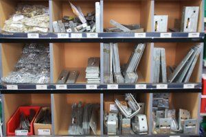 Shelves in a hardware store display assorted metal brackets, fasteners, and construction hardware in organized bins.