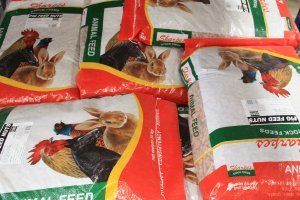 Stacked bags of Sharpe's brand animal feed, featuring illustrations of a rooster and a rabbit on the packaging.