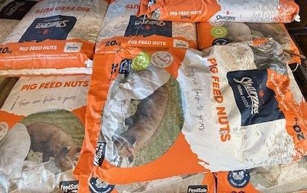 Several 20kg bags of Sharples Farm Feeds pig feed nuts arranged together.