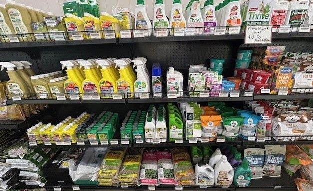 Shelves filled with various bottled gardening and lawn care products in a retail store aisle.
