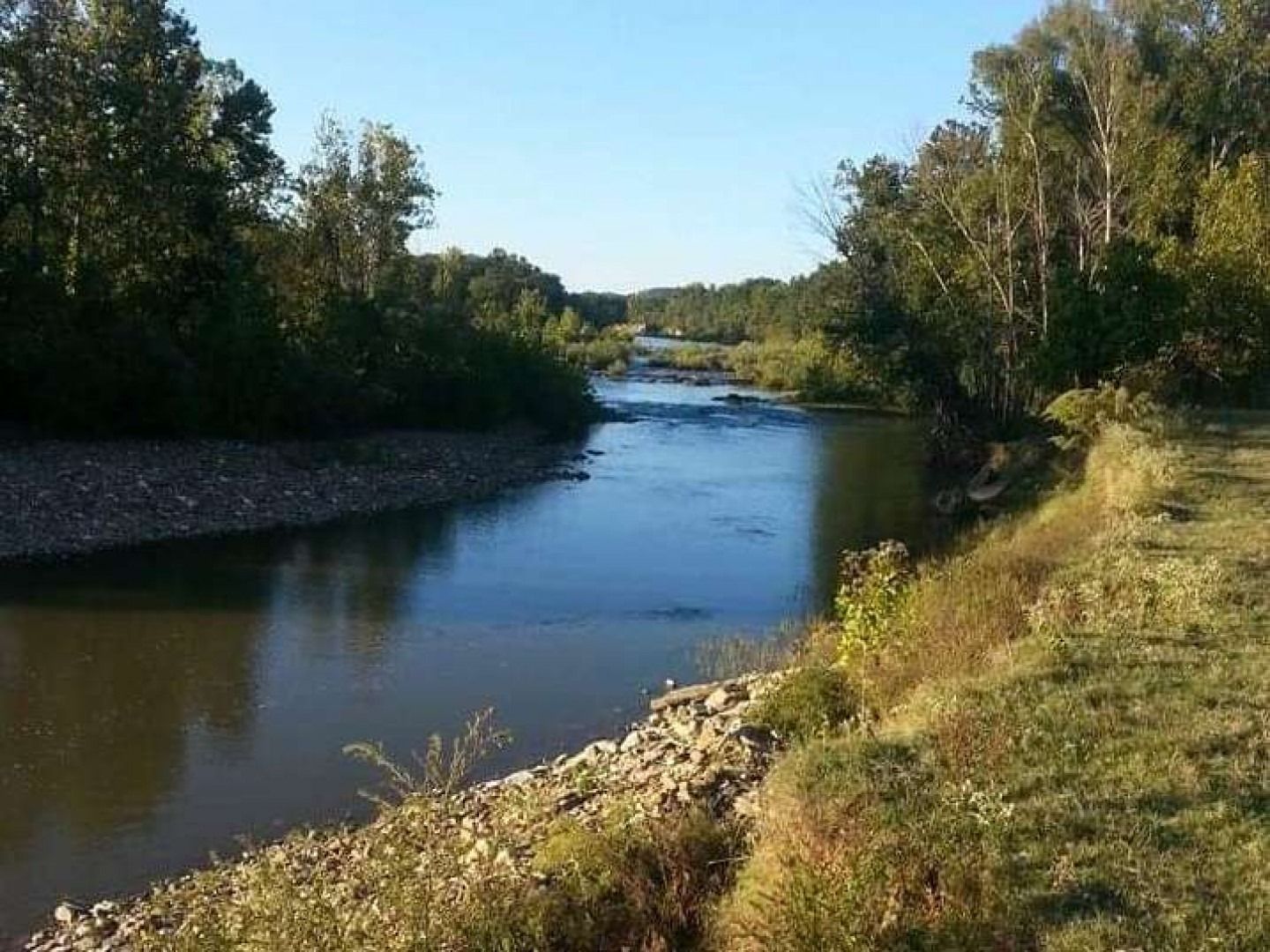 Calm river winding through a wooded landscape under a clear blue sky