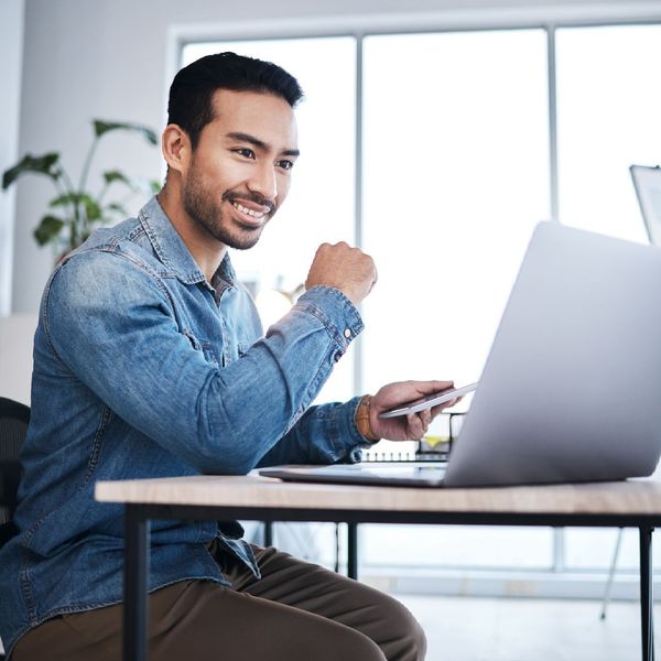 ein Mann sitzt an einem Schreibtisch und benutzt einen Laptop
