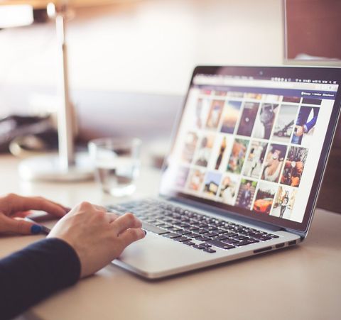 eine Person benutzt einen Laptop mit einer Auswahl an Bildern auf dem Bildschirm