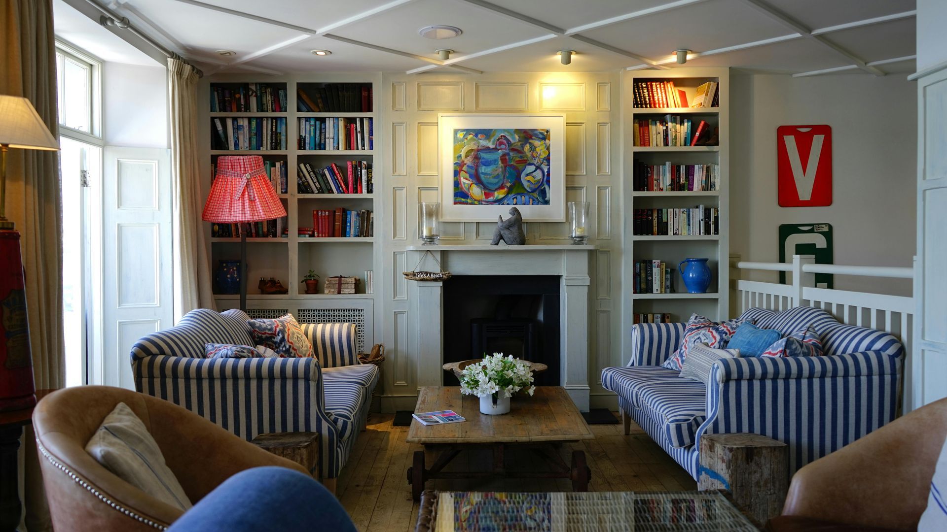 Cozy living room with striped sofas, bookshelves, fireplace, and a coffee table.