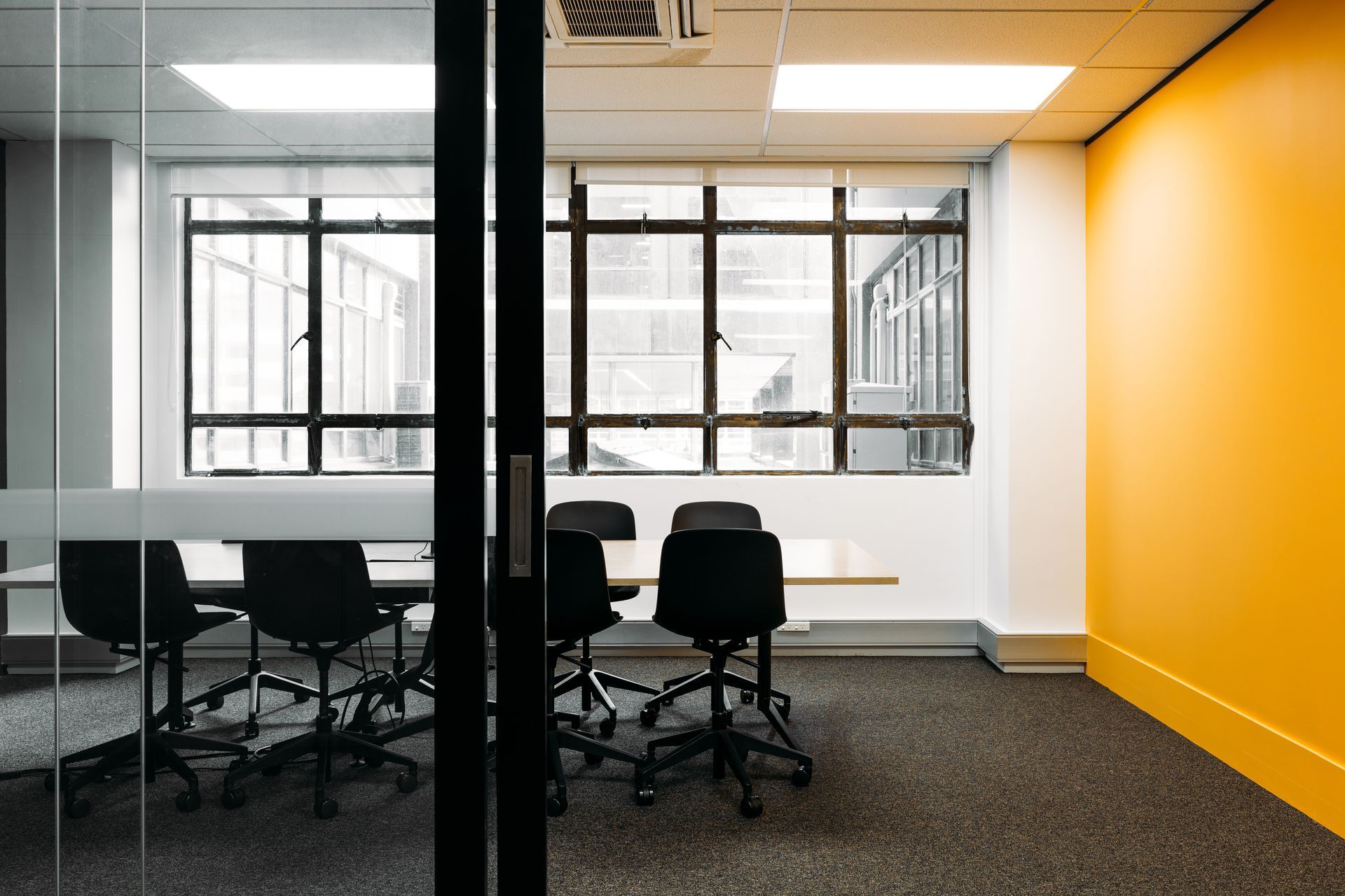 A conference room with a table and chairs and a yellow wall.