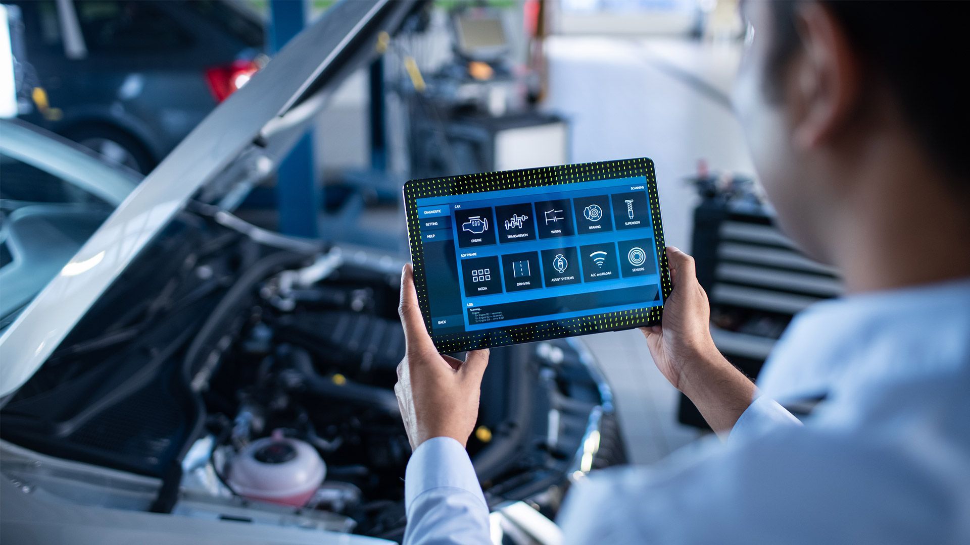 a man is holding a tablet in front of a car .