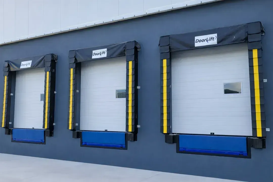 Tres puertas de carga azules y negras en la pared gris de un almacén