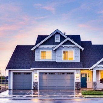 A large house with two garage doors and a blue door.