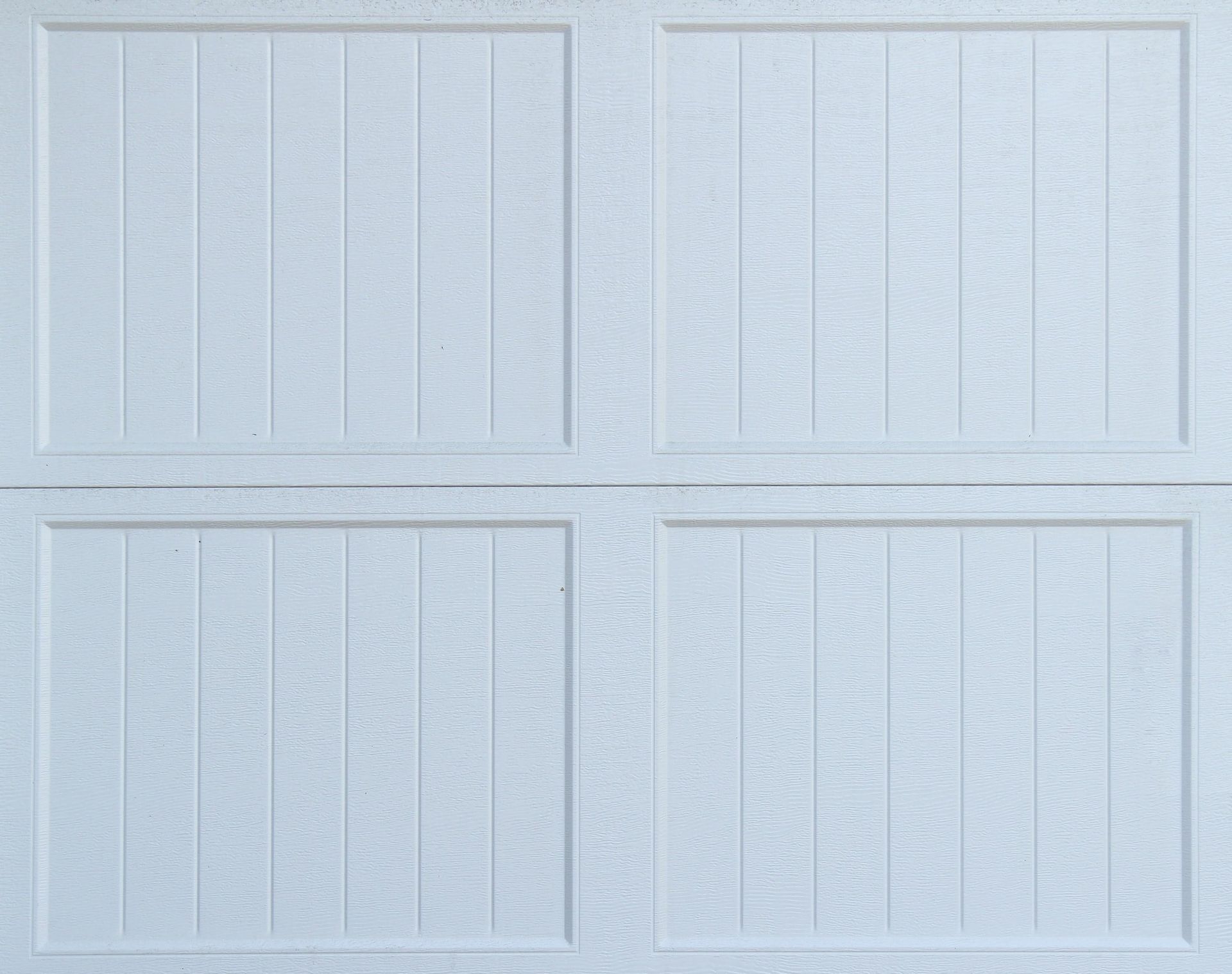 A close up of a white garage door with wood paneling.