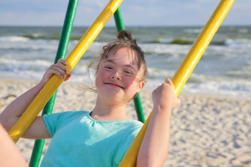 A Girl is Using a Swing Next to a Beach — Better Access Support Services In Stanthorpe, QLD