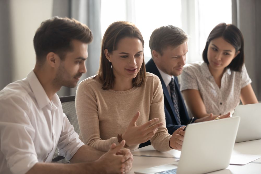 A Group of People Are Sitting at a Table Looking at a Laptop Computer — Better Access Support Services In Ipswich, QLD