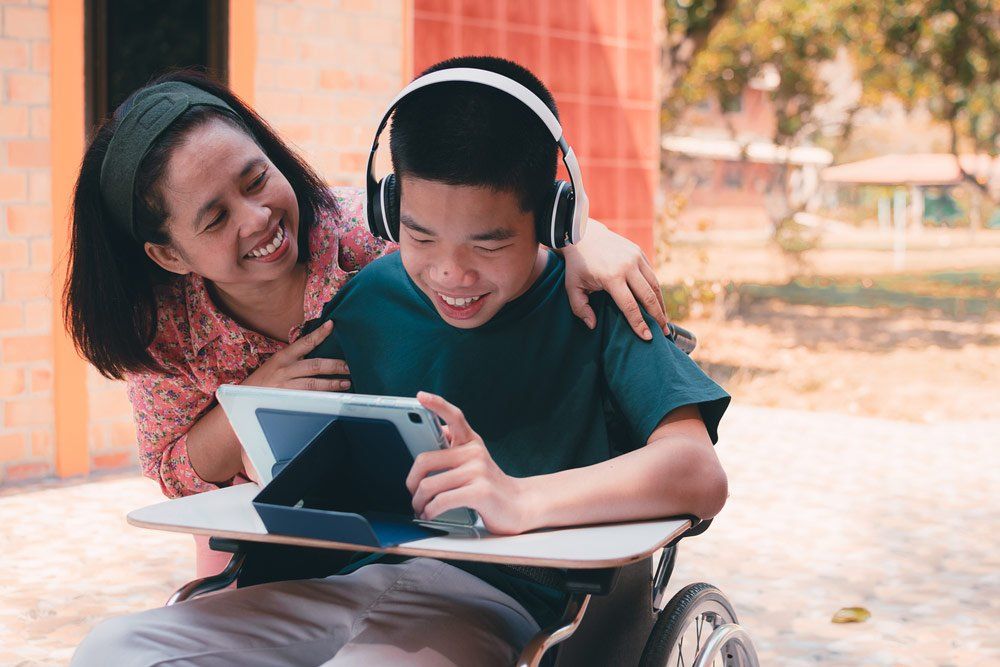 Child In Wheelchair Using Tablet — Better Access Support Services In Warwick, QLD