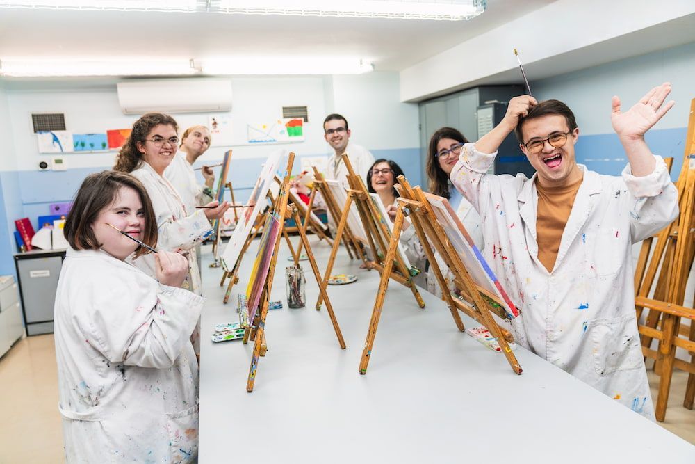 A Group of People Are Standing Around a Table With Easels — Better Access Support Services In Highfields, QLD