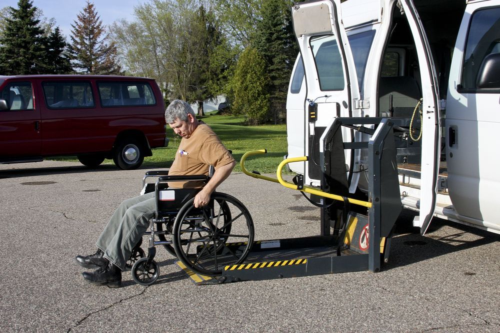A Man in a Wheelchair is Being Lifted Into a Van — Better Access Support Services In Dalby, QLD