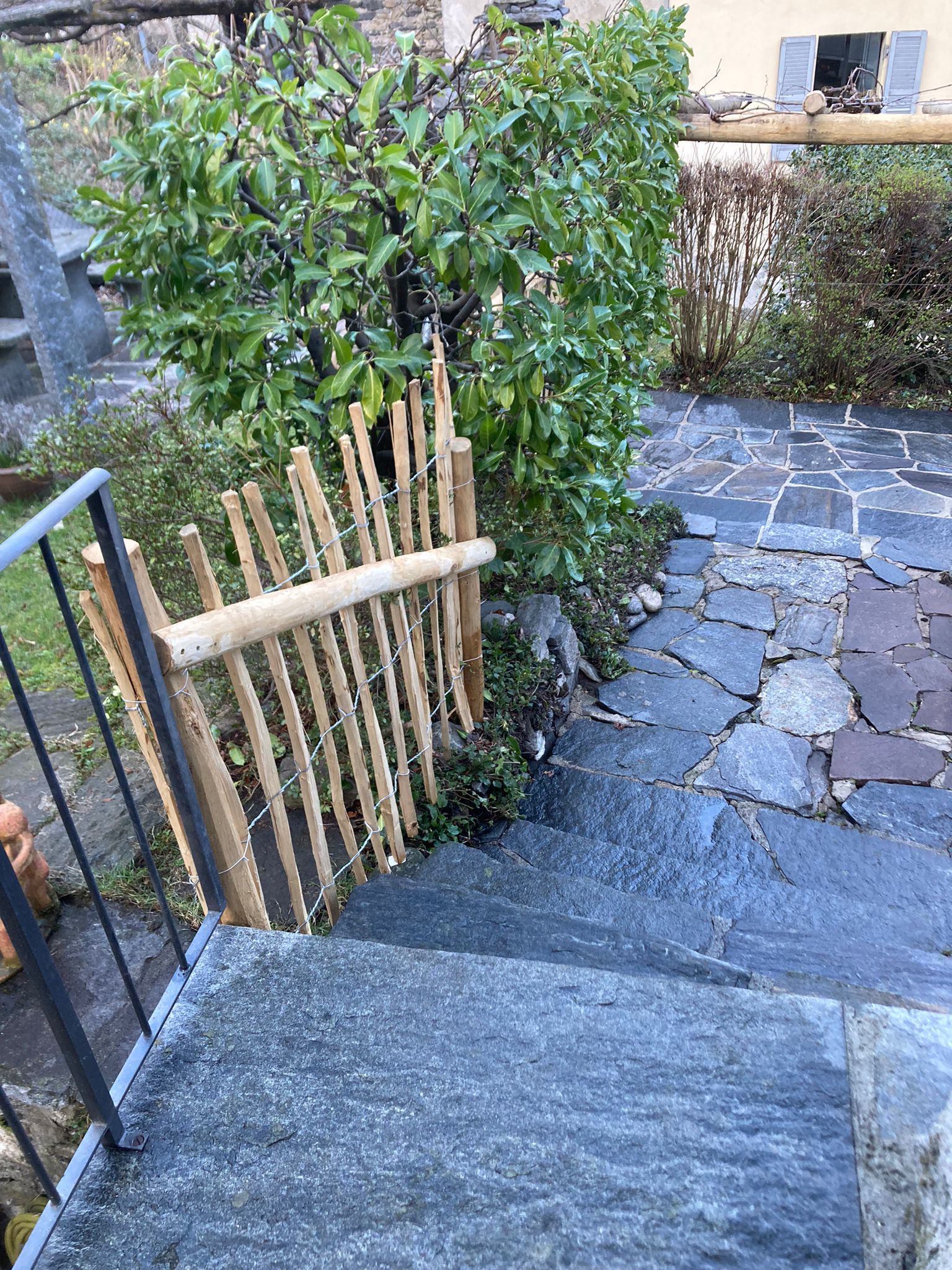 Una staccionata in legno circonda una rampa di scale in un giardino.