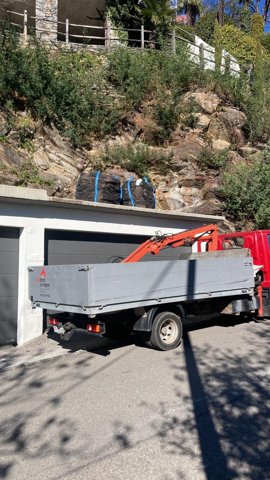 Davanti a un garage è parcheggiato un camion con una gru sul retro.