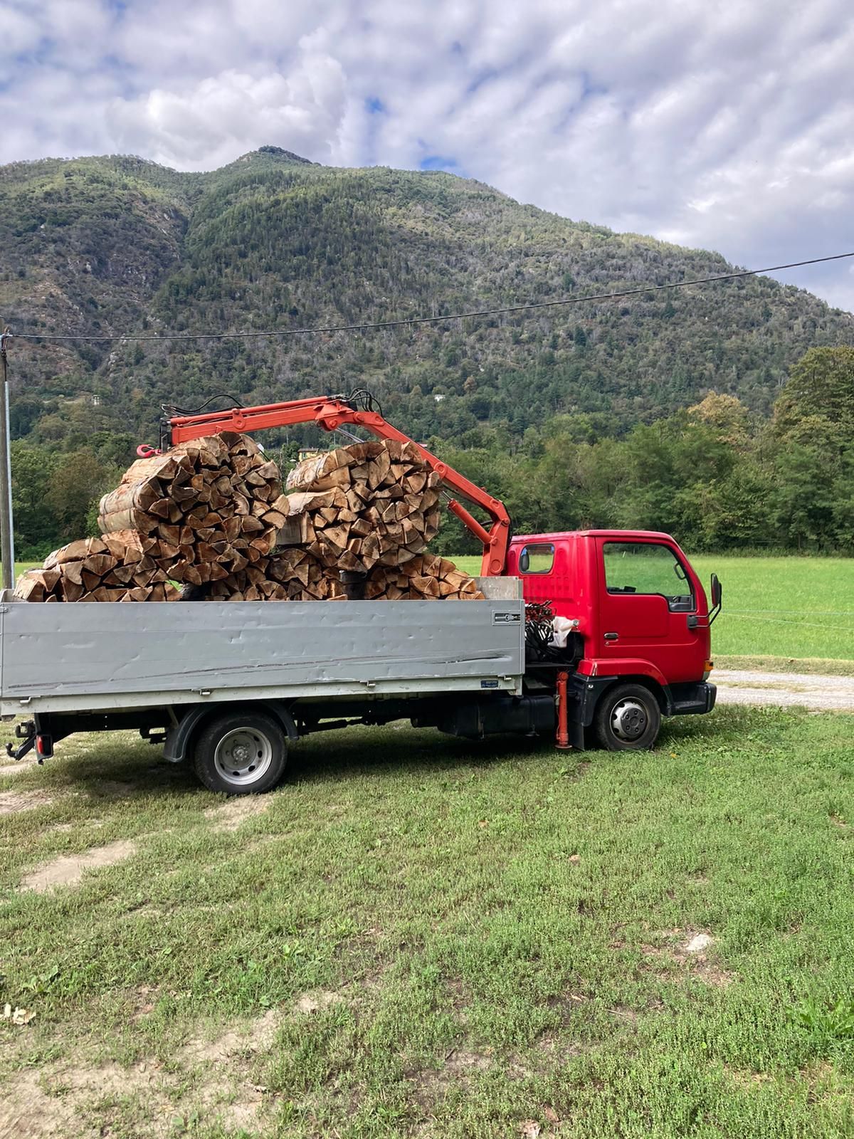 Un camion rosso trasporta una grande catasta di legna.