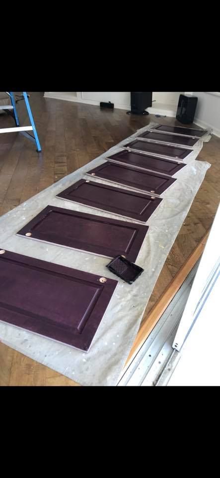 Purple painted cabinet doors laid out on a drop cloth.