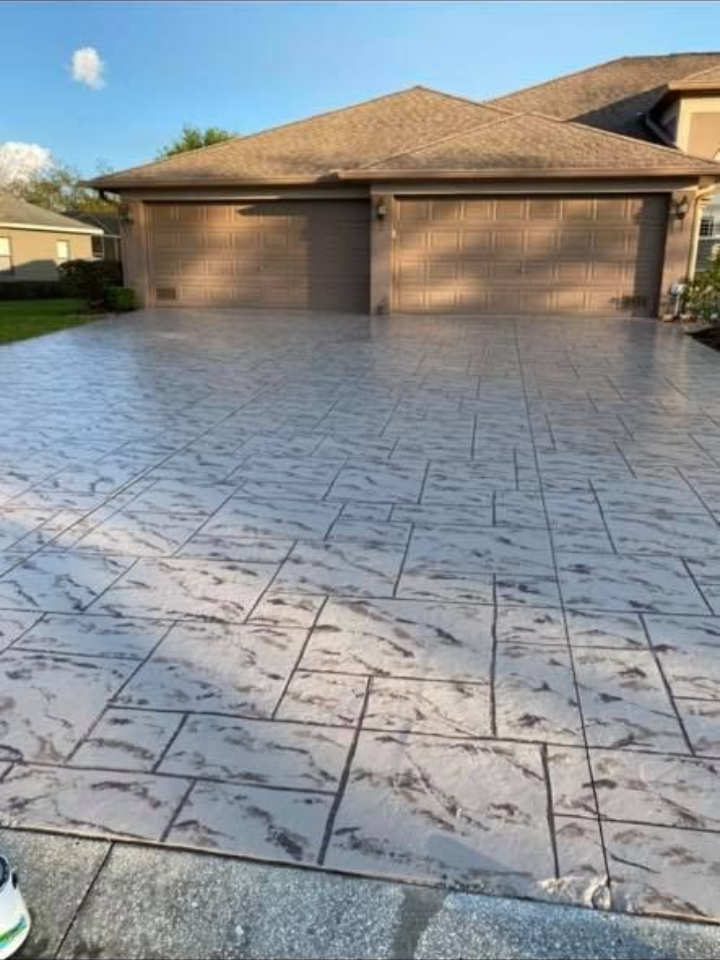 Stamped concrete driveway in front of a house with two garage doors.