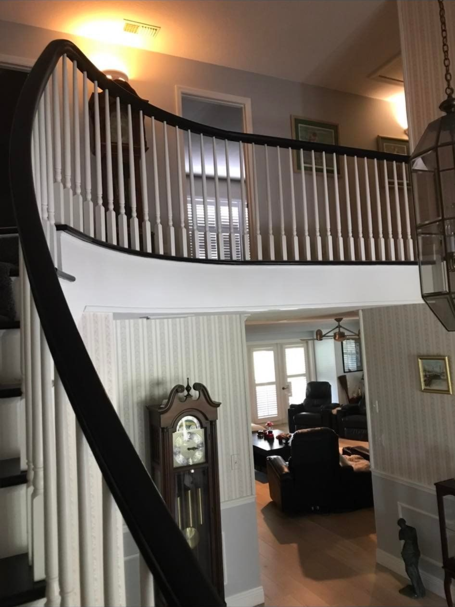 Curved staircase with black railing and white spindles, leading to a second-floor hallway.