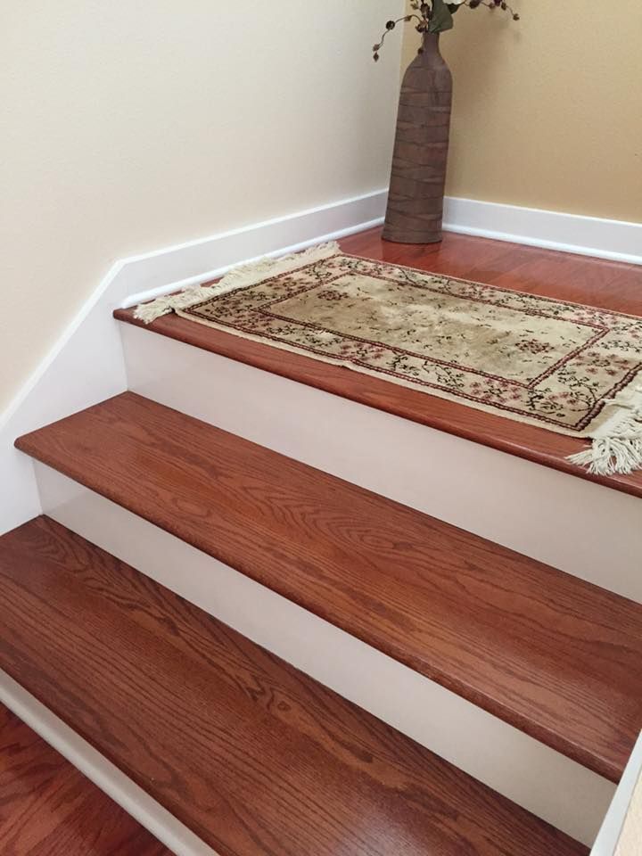 Wooden stairs with white risers, rug, and vase.