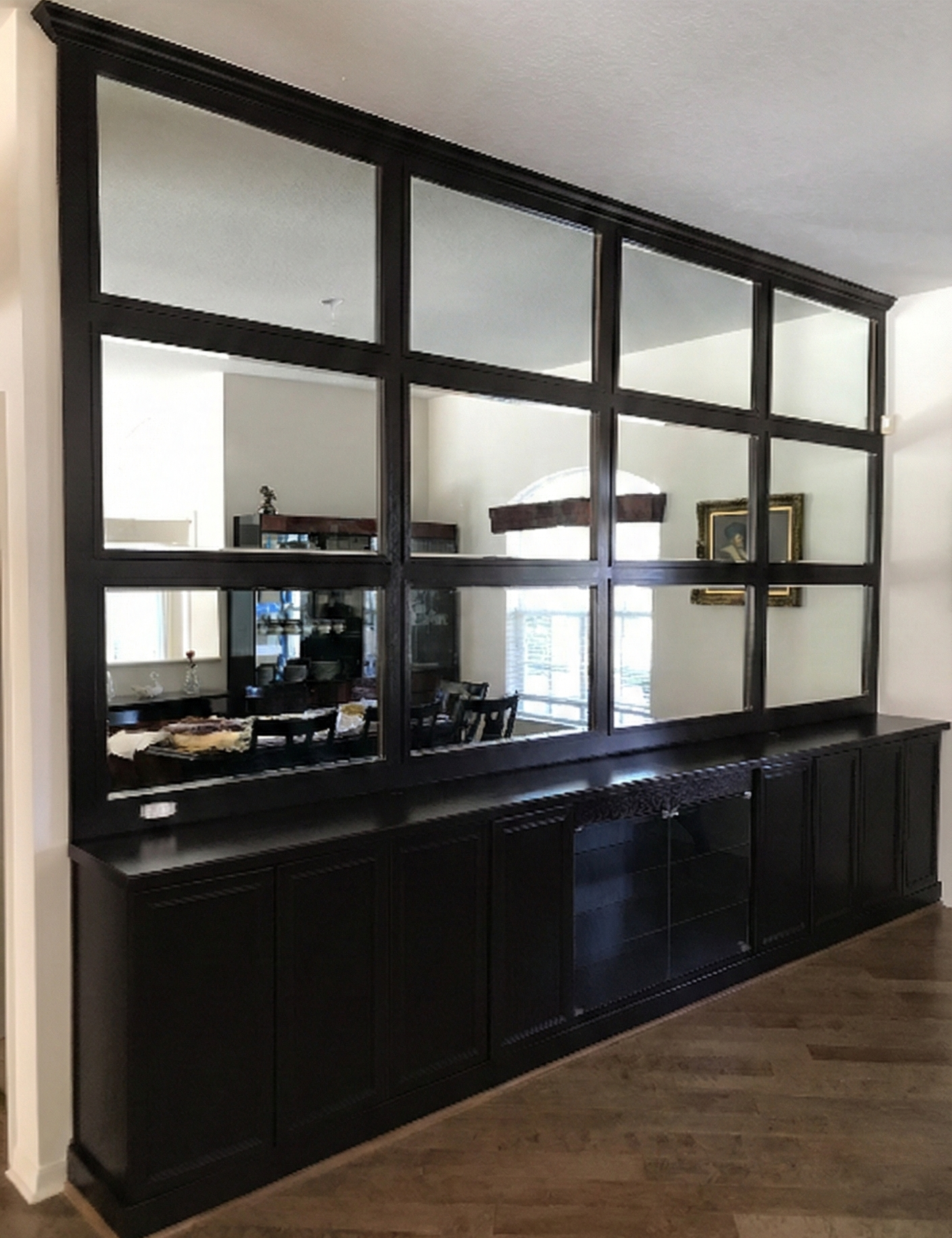 Dark wood cabinet with mirrored upper panel, dividing a room.
