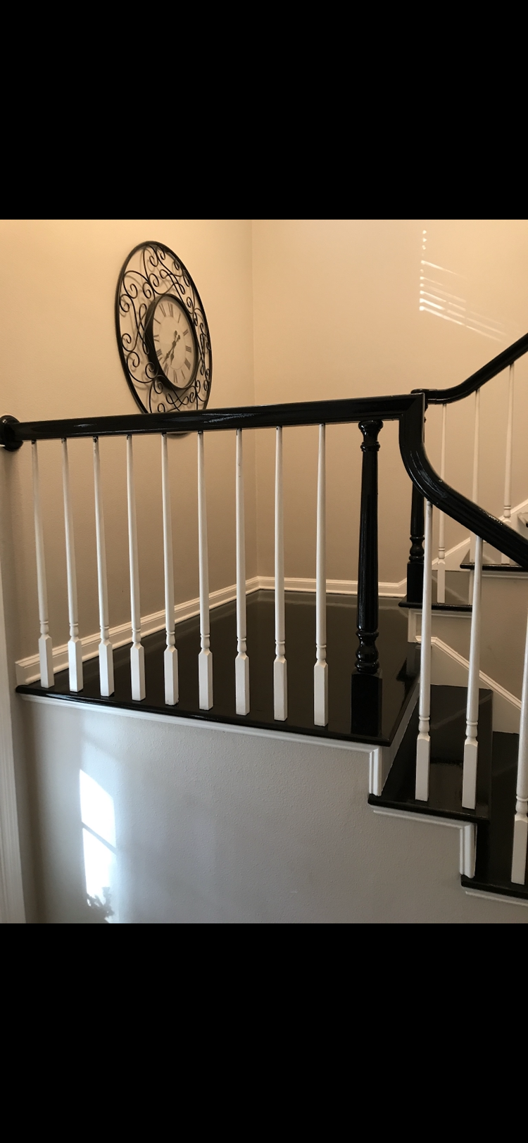 Staircase with black and white railing, black steps, and a decorative clock on the wall.