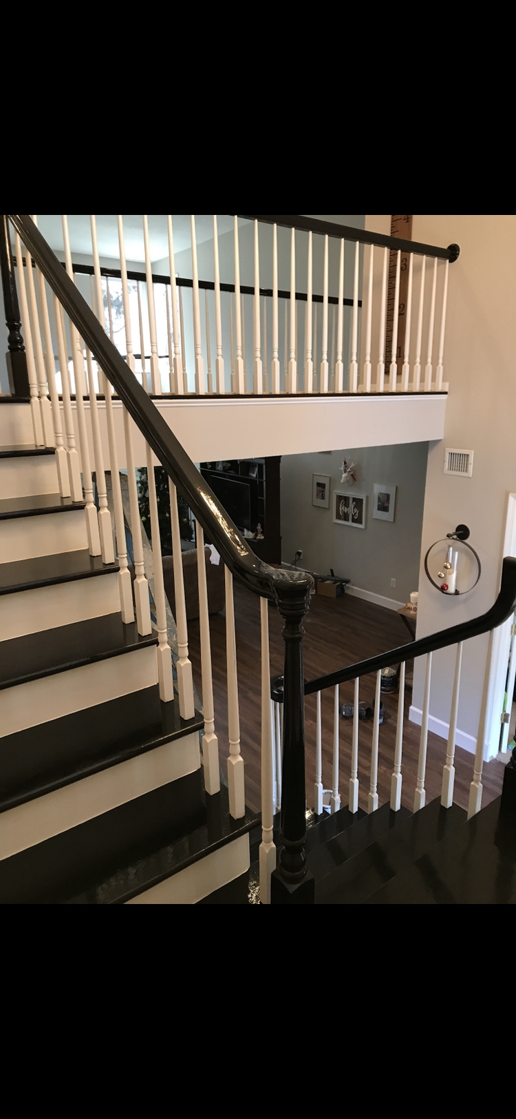 Staircase with black steps, white spindles, and dark handrails, leading to an upper level.