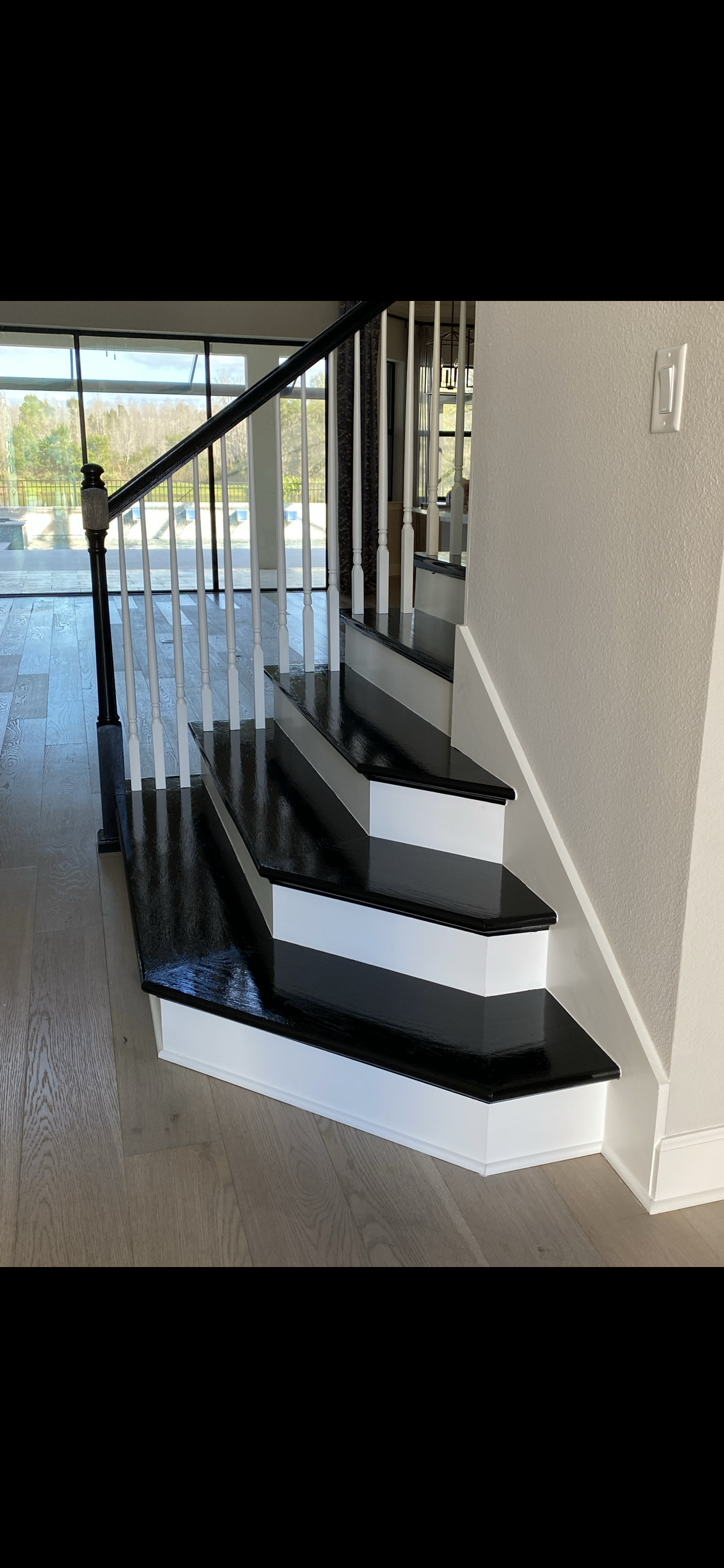 Black and white staircase with white risers and black treads, leading upwards next to a white wall.