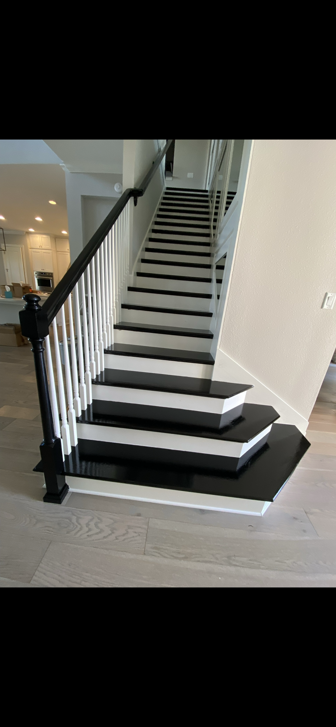Black and white staircase with white balusters. Dark wood railing and flooring.