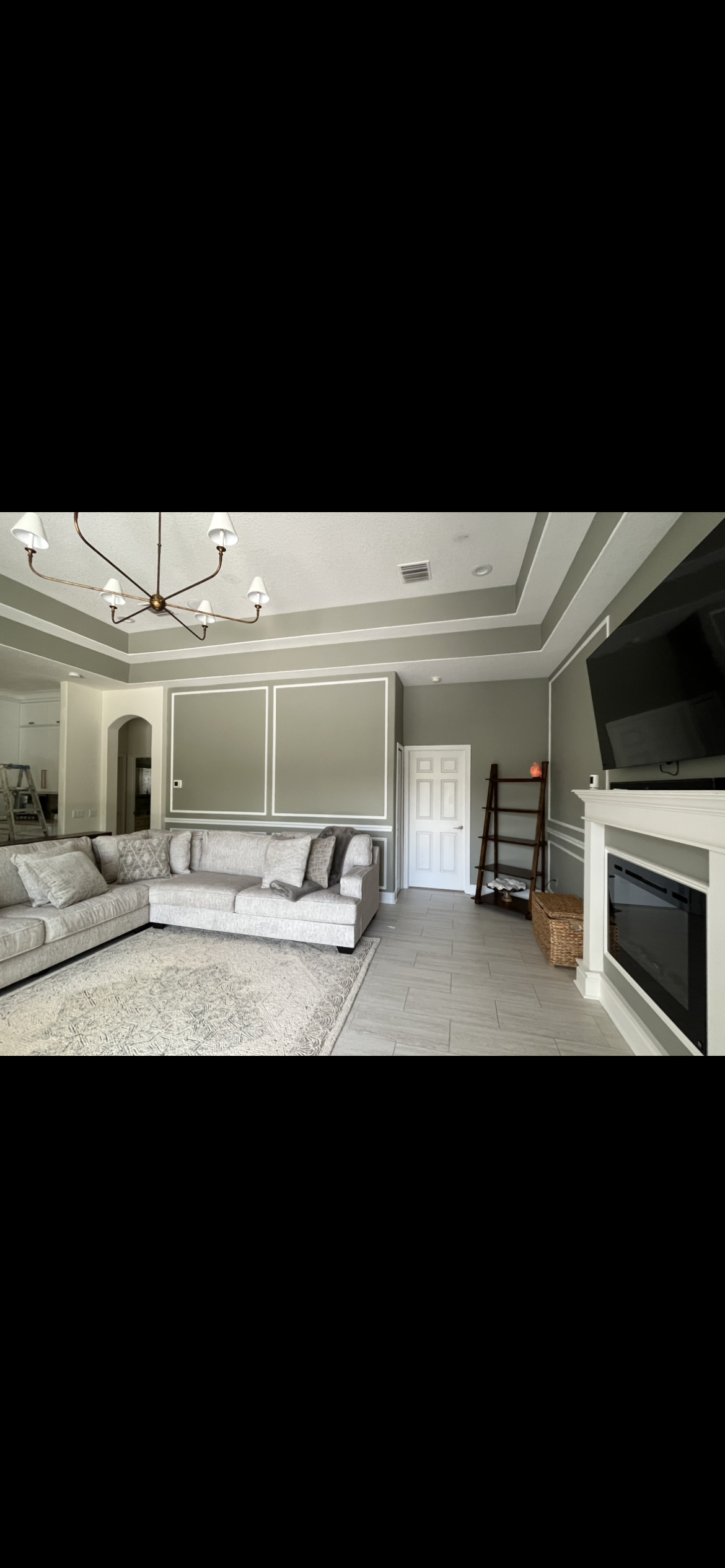 Living room with gray walls, sofa, fireplace, and chandelier.