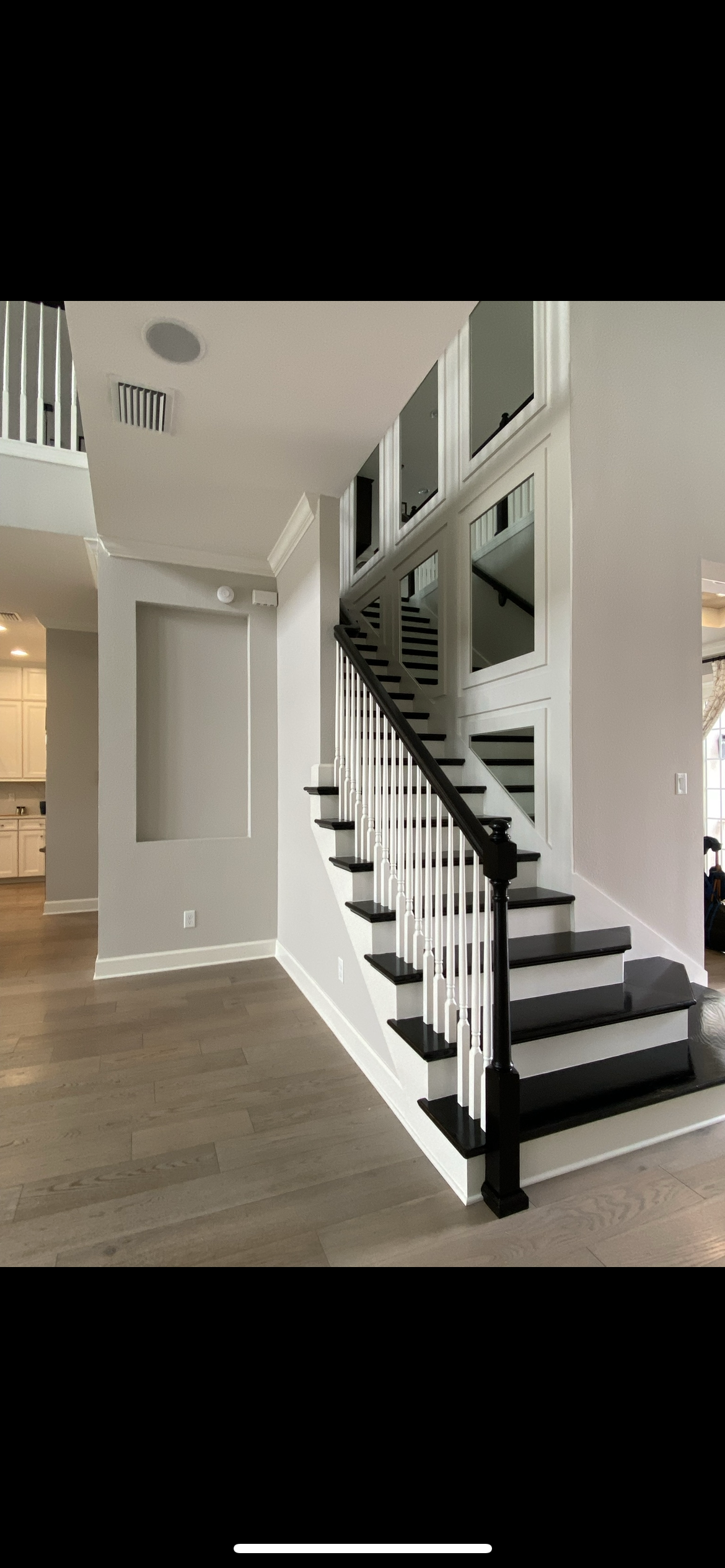 A curved staircase with black steps, white risers, and a black handrail in a modern home.